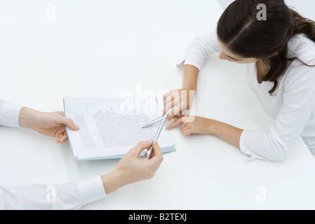 Man holding document, woman carefully reading it, high angle view Stock Photo