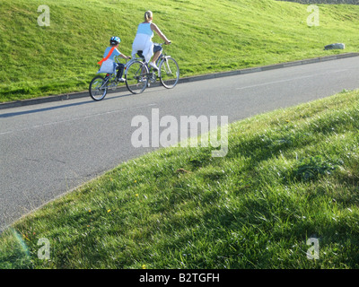 mother and child riding a bike on street road in country Stock Photo