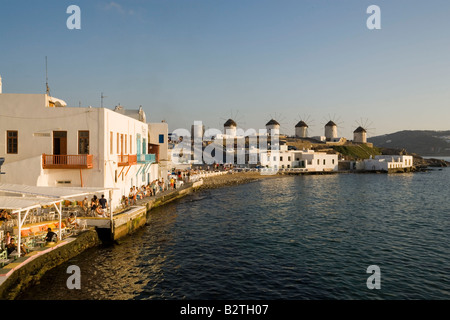 People sitting in restaurants and bars directly at sea, windmills in background, Little Venice, Mykonos-Town, Mykonos, Greece Stock Photo
