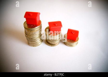 Small red model houses stacked on top of piles of coins isolated objects Property ladder Housing market credit crunch concepts Stock Photo