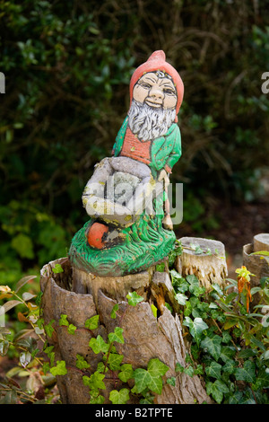 A garden gnome pushing a wheel barrow on top of a tree stump in an Essex Garden Stock Photo