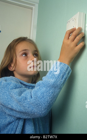 girl turning down the central heating thermostat Stock Photo