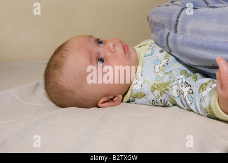 Baby Boy Joshua Kailas Hudson Aged 15 Weeks Lying in Bed Looking Up with a Bored Pout on Lips Stock Photo