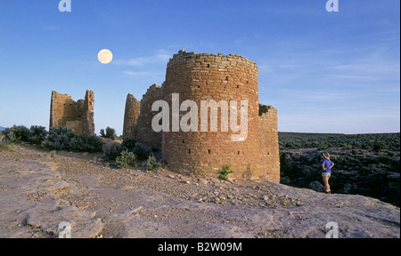 Moonrise as a hiker examines the ancient Anasazi Indian ruins of a clifftop tower in Hovenweep National Monument, square tower Stock Photo