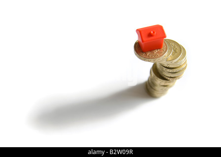 Small red model houses stacked on top of piles of coins isolated objects Property ladder Housing market credit crunch concepts Stock Photo