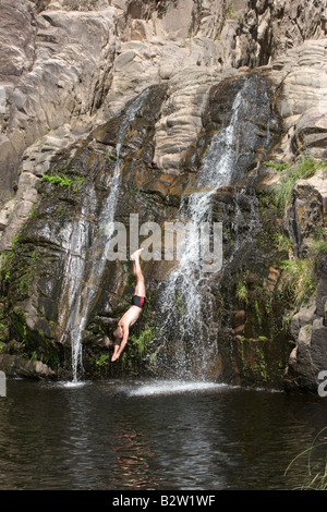 A diver jumping from a high rock in Cascada del Toro Muerto waterfall near Mina Clavero, Traslasierra, Cordoba, Argentina Stock Photo