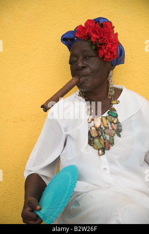 Cuban woman wearing a Santeria white dress smoking a big cigar in Havana, Vieja Havana in Cuba. Stock Photo