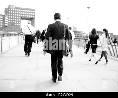 commuters walking over London bridge people walking to work man in suit walking woman walking rushing to work man walking Stock Photo