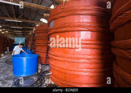 Man supervises large vats of fermenting fish sauce at factory Phu Quoc Island Vietnam Stock Photo