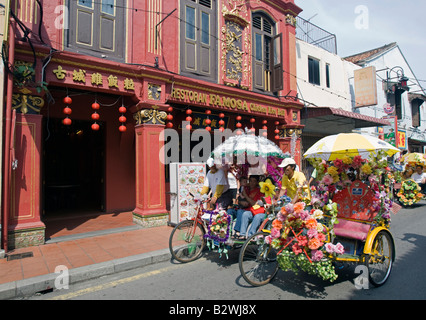 Tourist rickshaws pass well known chicken rice ball Famosa Restaurant Malacca Malysia Stock Photo