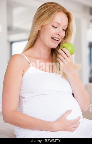 Pregnant woman eating apple and smiling Stock Photo