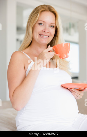 Pregnant woman with cup of tea smiling Stock Photo