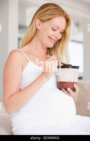 Pregnant woman with bucket of ice cream smiling Stock Photo