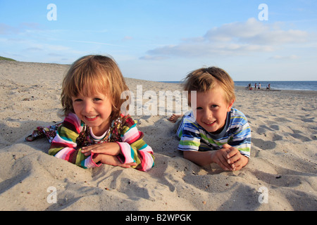 Girl and boy lying in sand on a beach