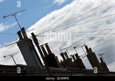 TV aerials and chimneypots on the skyline above a row of terraced houses Stock Photo