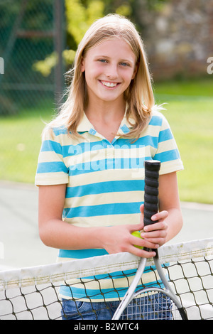 Young girl with racket on tennis court smiling Stock Photo