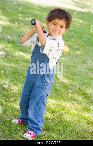 Young boy holding baseball bat outdoors smiling Stock Photo