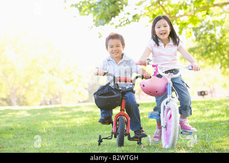 Brother and sister outdoors on bicycles smiling Stock Photo