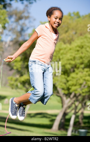 Young girl using skipping rope outdoors smiling Stock Photo