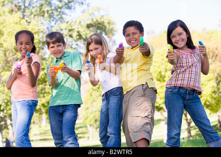 Five young friends with water guns outdoors smiling Stock Photo