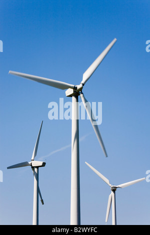 Three Wind turbines sustainable electricity generators for alternative energy on wind farm close-up against blue sky. North Wales UK Britain Stock Photo