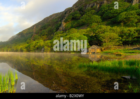 A small boathouse on a beautifully calm and misty morning at Llyn Dinas in Snowdonia national park North Wales