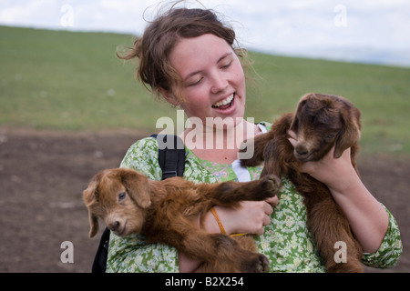 Female backpacker holding two baby goats on a visit to a ger Stock Photo