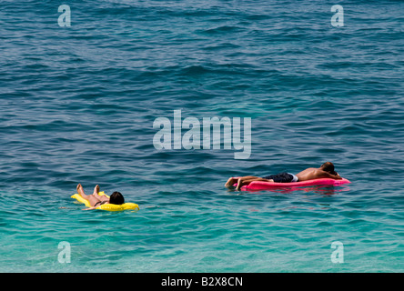 relaxing on lilos in the water at Petani beach Paliki Cephallonia Greece Stock Photo