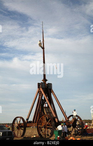 Huge iron wheeled Yankee Siege Trebuchet with person at top of climbing pins on top of arm. Stock Photo