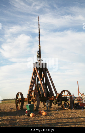 Huge iron wheeled Yankee Siege Trebuchet with person standing on tiny ledge at bottom of tall arm secured with safty rope. Stock Photo