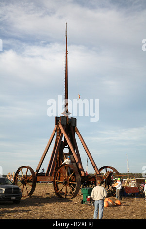 Huge iron wheeled Yankee Siege Trebuchet with person standing on frame holding onto the top of the back wheel. Stock Photo