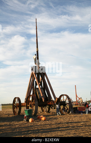 Huge iron wheeled Yankee Siege Trebuchet with person standing on tiny ledge at bottom of tall arm Stock Photo