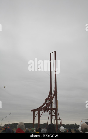 Large arching metal framed trebuchet with firing arm pointing forwards, pumpkin released from sling too early and heads backward Stock Photo