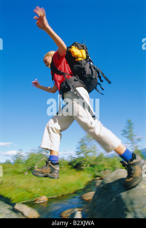 Woman hiking outdoors jumping over stream (blur) Stock Photo