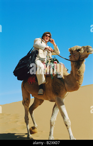 Man outdoors in the desert using a cellular phone on a camel Stock Photo