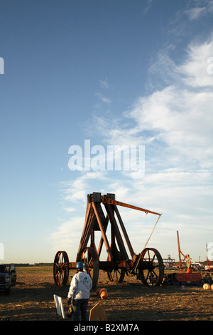 Huge iron wheeled Yankee Siege Trebuchet with fling arm just beginning to rise, with pumpkin dragging along ground under machine Stock Photo