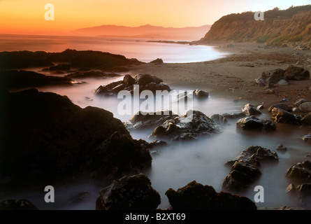 Waves painting rocky beach along Big Sur coast of California at sunset Stock Photo