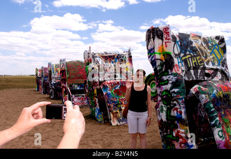 Tourist taking picture with camera at the Cadillac Ranch with buried cars in ground in Amarillo Texas USA Stock Photo