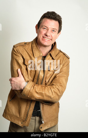 Man in his 40s smiling wearing a leather jacket -arms crossed Stock Photo