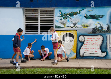 School children playing in playground beside socialist propaganda mural paintings Viñales Cuba Stock Photo