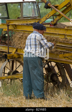 French peasant working on old straw baler machine at agricultural show, Indre, France. Stock Photo