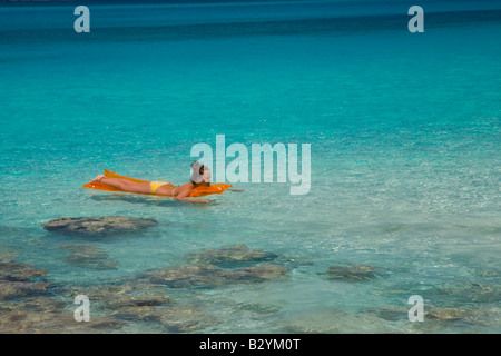 Woman floating on air mattress at Cinnamon Bay in the Virgin Islands National Park on the Caribbean island of St John in the US Stock Photo