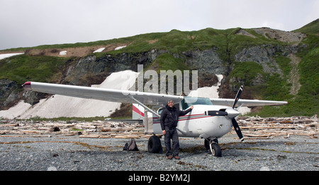 K-Bay Air air plane (Cessna 206) and pilot standing on a gravel beach of the Katmai National Park and Preserve, Alaska, US Stock Photo