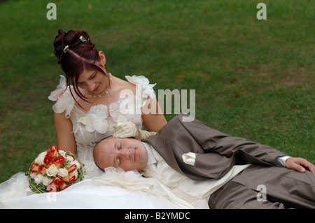 Newlywed couple with husband asleep on his wife in bench's park, France Stock Photo