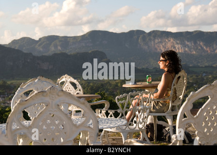 Model Released European tourist enjoying the view across a valley to steep mogote limestone hills of Viñales Cuba Stock Photo