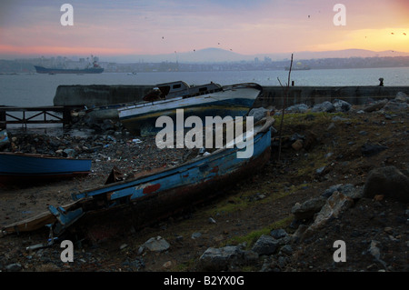 Rickety old boats sit upon the shore as the sun rises over the Bosphorus early on a Winter morning in Sultanahmet, Istanbul. Stock Photo