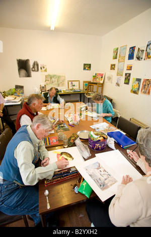 group of students sat around a table working on their art work. in an art class Stock Photo