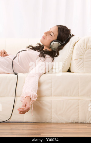 Woman Listening to Music with Headphones on Sofa Stock Photo