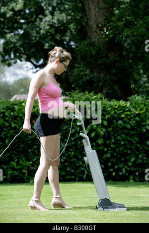 Pregnant Woman Mowing Lawn with Vaccuum Cleaner Stock Photo