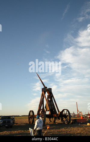 Huge iron wheeled Yankee Siege Trebuchet with pumpkin shattered into thousands of pieces which are blowing back towards machine. Stock Photo